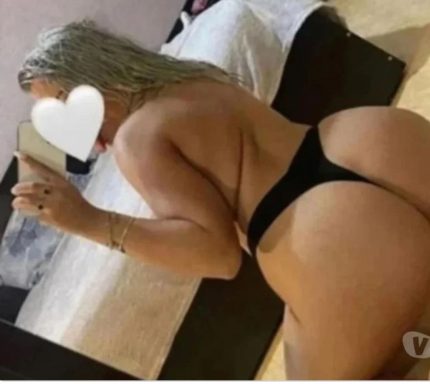 A person posing in a provocative manner on a bed, partially covered.